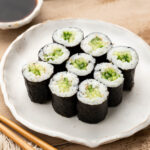 Close up of sushi rolls with soy sauce, wasabi, chopsticks, and a cloth.