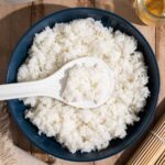 A blue bowl filled with seasoned sushi rice, ready to be used for homemade sushi.