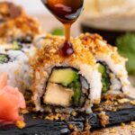 Tofu crunch sushi roll drizzled with a spoonful of teriyaki sauce.