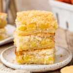 Stack of three pineapple coconut squares on a small white plate.