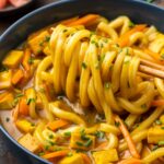 Vegan Japanese curry udon noodle pull with chopsticks.